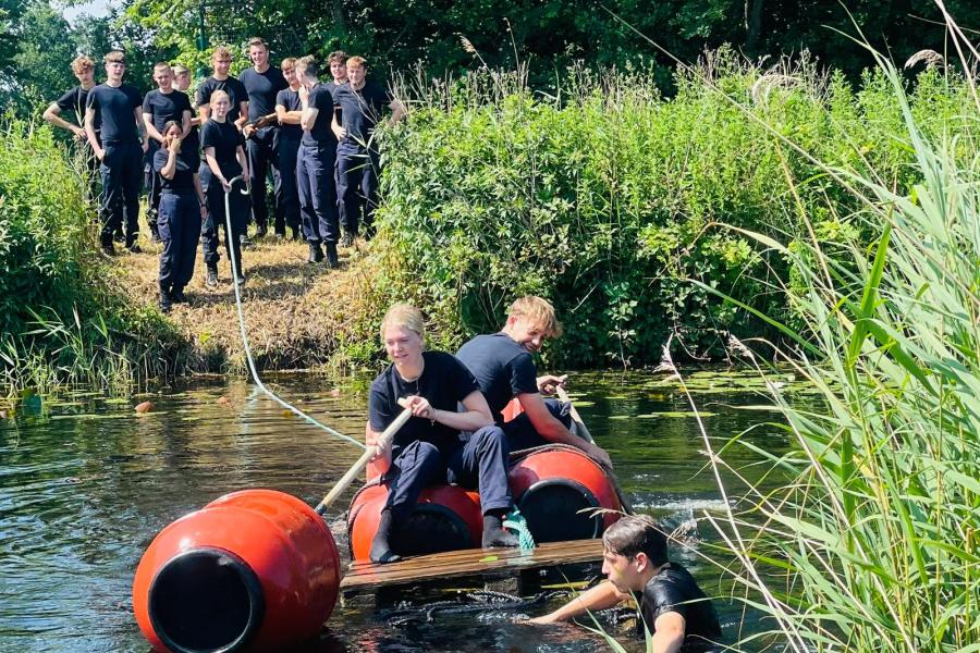 studenten steken water over op zelfgemaakte vlotten 