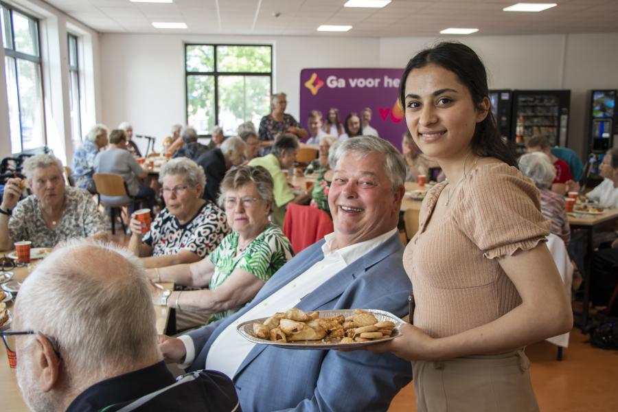 stagiair geeft eten aan oudere 