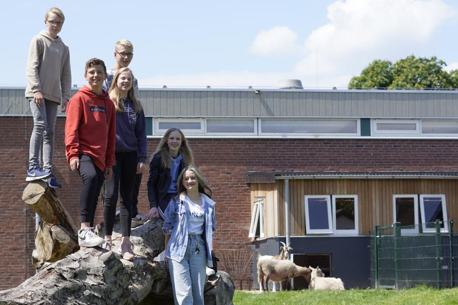 leerlingen voor school Vonk staan op boomstam