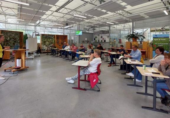 Groep luistert naar een vrouw in de kas 